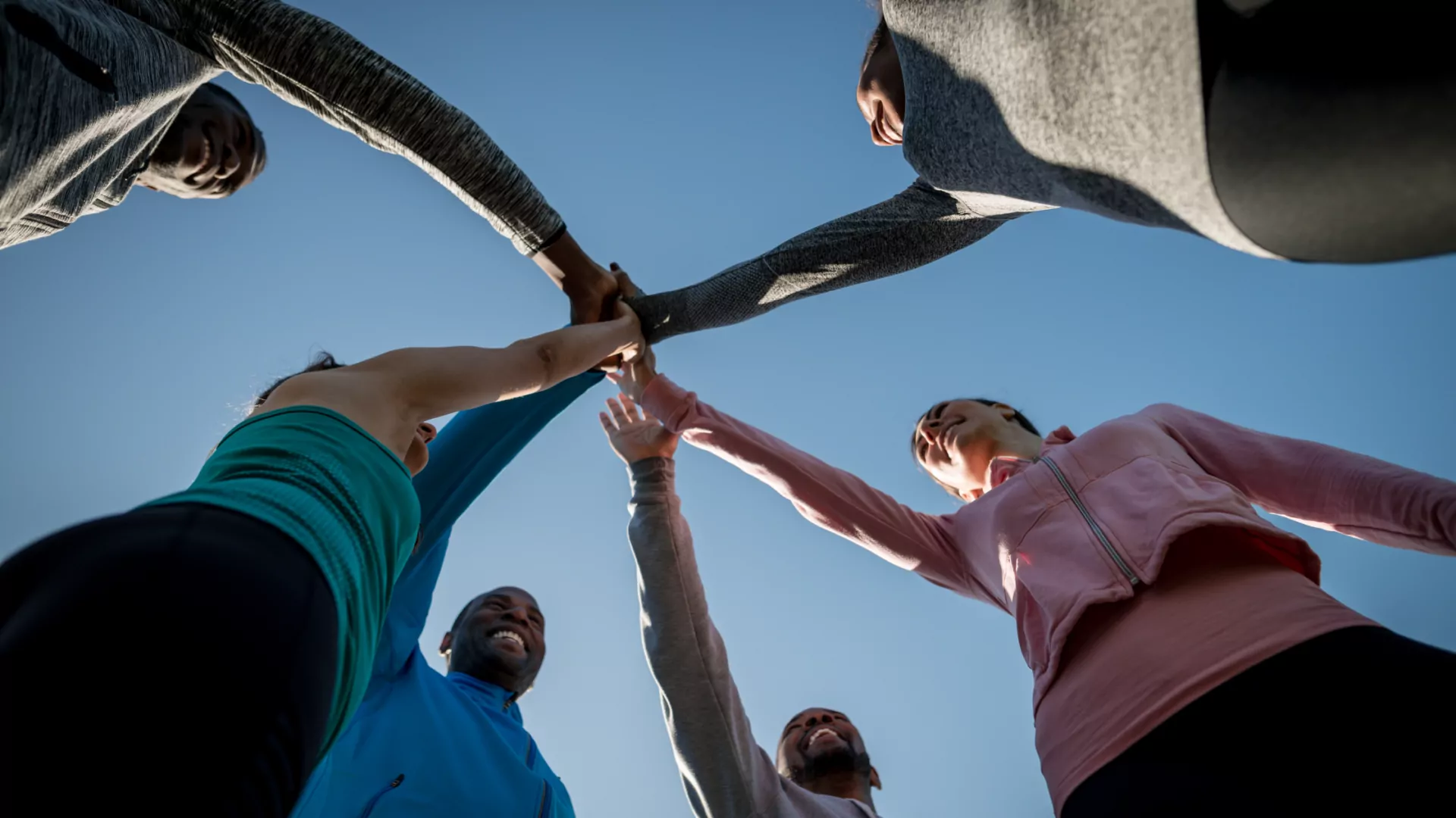 a team of people joining hands in the center in unity before doing a sport or physical activities