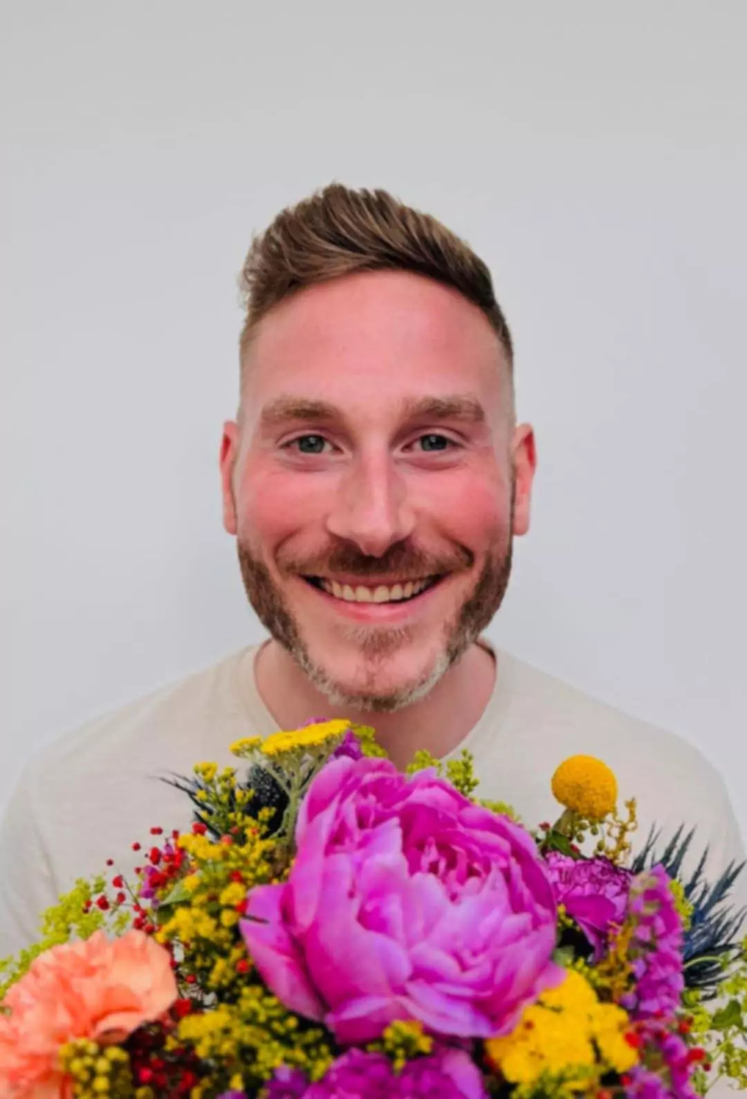A portrait of ALGSO coach Maxime Dierickx, smiling and holding a bouquet of flowers.